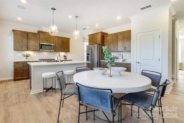 dining area featuring light wood-type flooring, ornamental molding, and sink