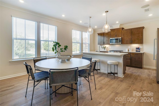 dining room featuring crown molding, sink, and light hardwood / wood-style floors