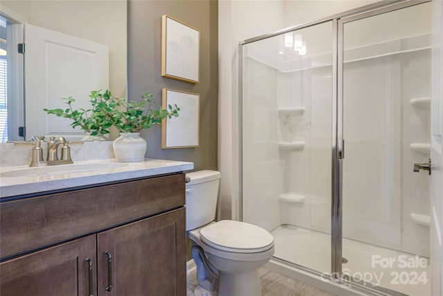 bathroom featuring vanity, toilet, and a shower with shower door