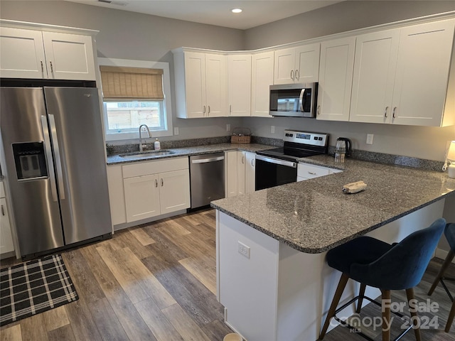 kitchen with kitchen peninsula, appliances with stainless steel finishes, light hardwood / wood-style floors, and sink