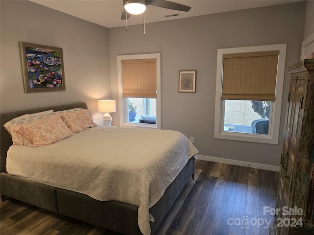 bedroom featuring ceiling fan, dark hardwood / wood-style flooring, and multiple windows