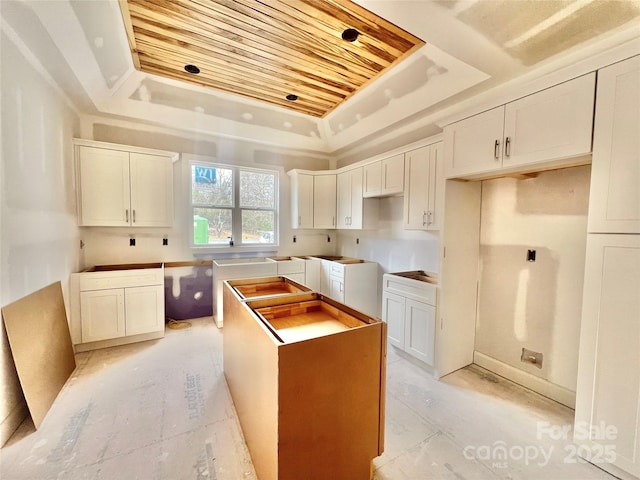 kitchen with wooden ceiling, a raised ceiling, white cabinets, and a center island