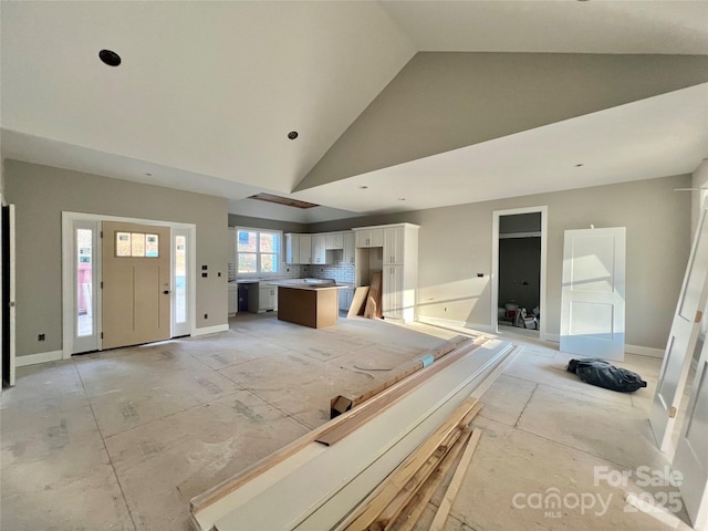 unfurnished living room with baseboards and high vaulted ceiling