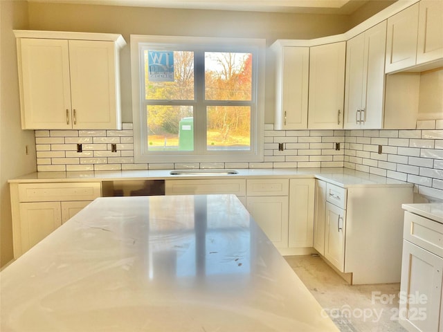 kitchen with backsplash, light countertops, and a sink