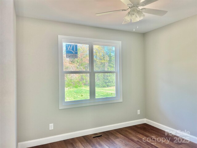 spare room with dark wood finished floors, baseboards, visible vents, and a ceiling fan