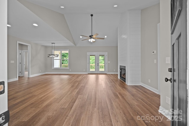unfurnished living room featuring a fireplace, high vaulted ceiling, a ceiling fan, baseboards, and light wood-type flooring