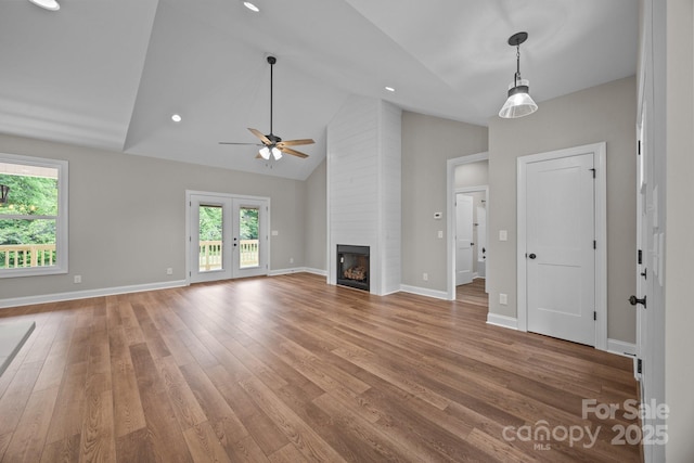 unfurnished living room featuring plenty of natural light, light wood finished floors, ceiling fan, and a large fireplace