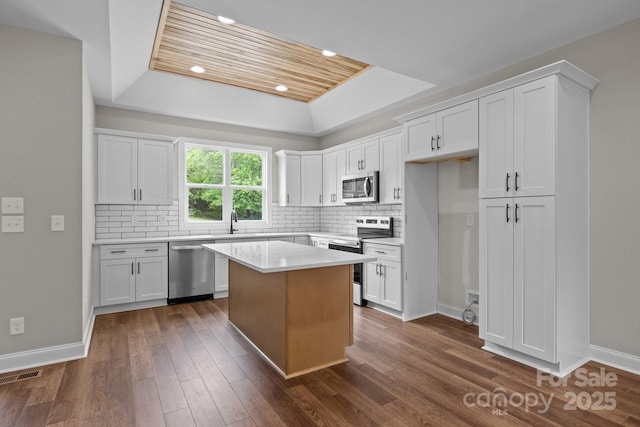 kitchen with visible vents, white cabinetry, appliances with stainless steel finishes, and a tray ceiling