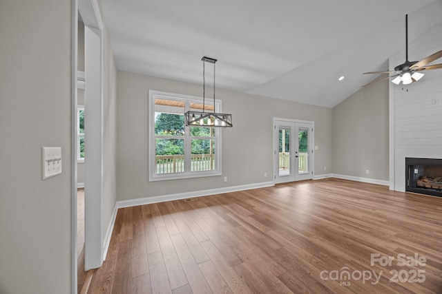 interior space featuring a fireplace, baseboards, lofted ceiling, and light wood-style floors