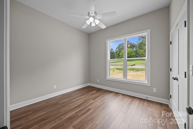 spare room with baseboards, ceiling fan, wood finished floors, and visible vents