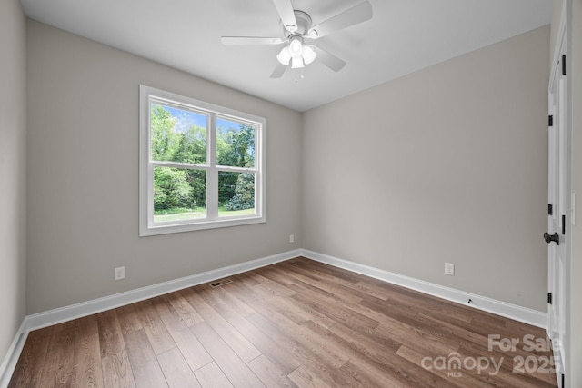 spare room with visible vents, a ceiling fan, baseboards, and wood finished floors