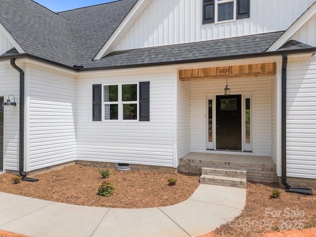 property entrance with board and batten siding and roof with shingles