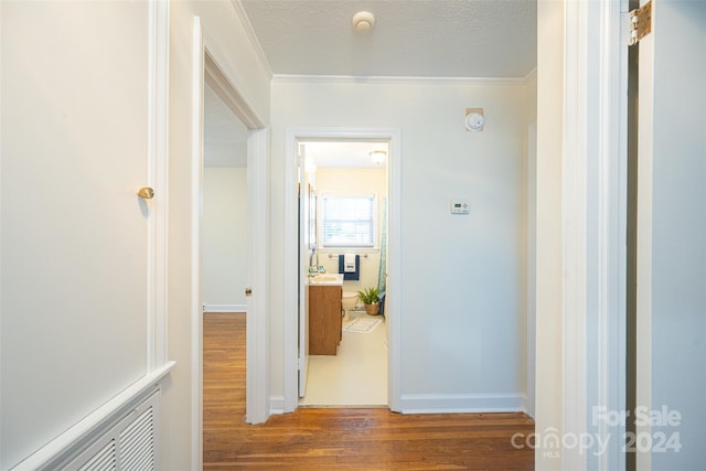 hallway featuring a textured ceiling, dark hardwood / wood-style flooring, and crown molding