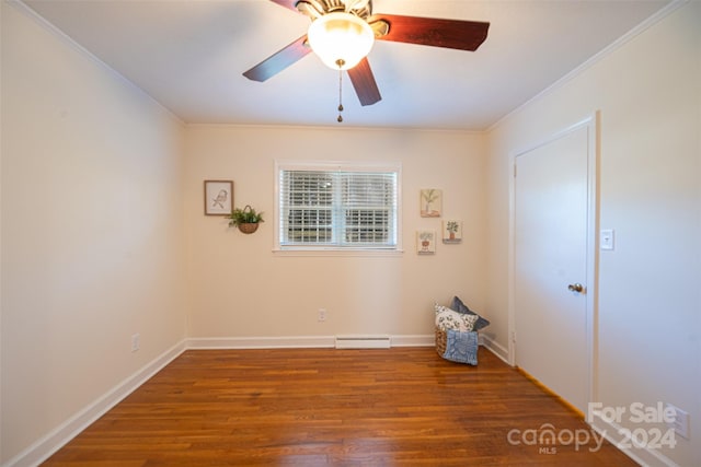 spare room featuring crown molding, ceiling fan, dark hardwood / wood-style floors, and a baseboard heating unit