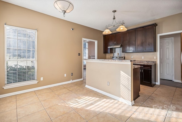 kitchen featuring dark brown cabinetry, a center island, hanging light fixtures, a textured ceiling, and light tile patterned floors