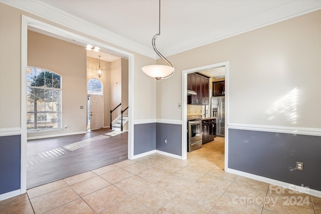 unfurnished dining area featuring light hardwood / wood-style flooring, crown molding, and a notable chandelier