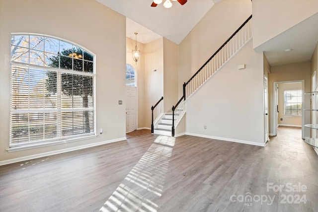 entryway with a wealth of natural light, high vaulted ceiling, and hardwood / wood-style flooring