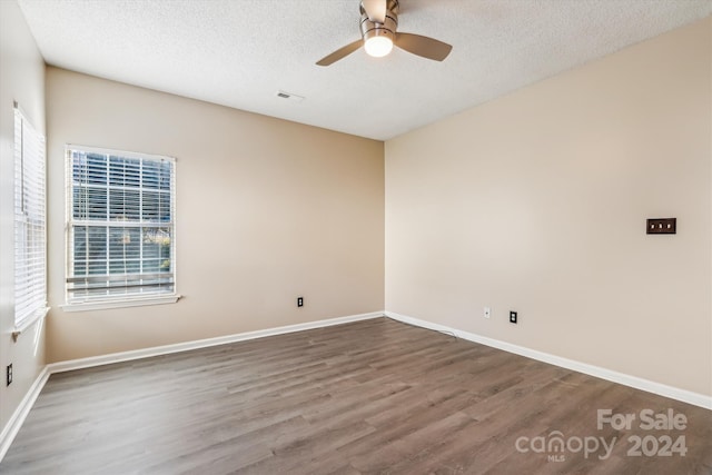 unfurnished room with a wealth of natural light, hardwood / wood-style floors, ceiling fan, and a textured ceiling