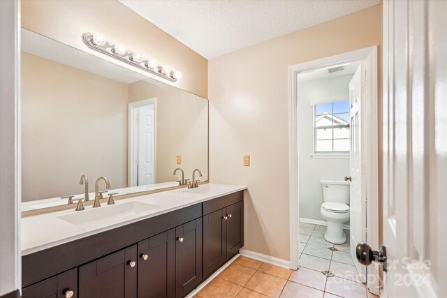 bathroom featuring tile patterned flooring, vanity, toilet, and a textured ceiling