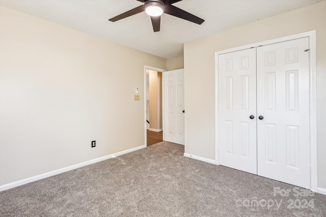 unfurnished bedroom with carpet flooring, ceiling fan, a closet, and a textured ceiling