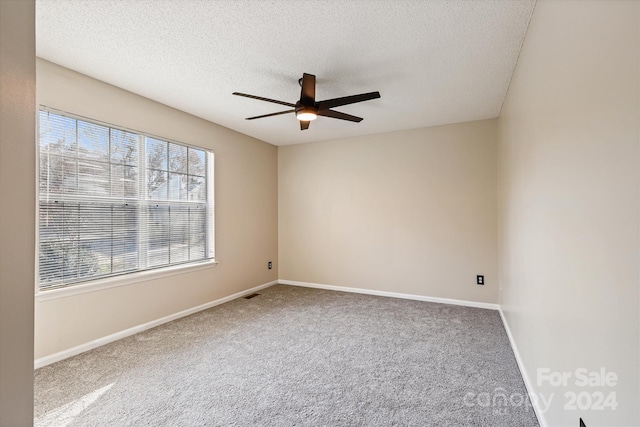 carpeted spare room featuring ceiling fan and a textured ceiling