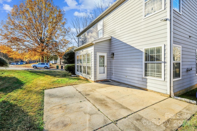 view of side of property featuring a patio area and a lawn