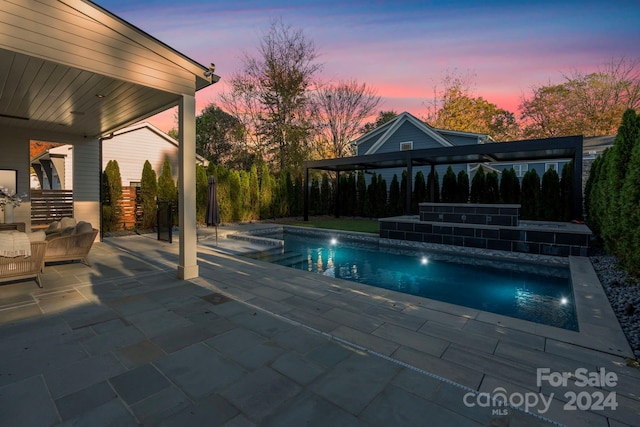 pool at dusk featuring a patio