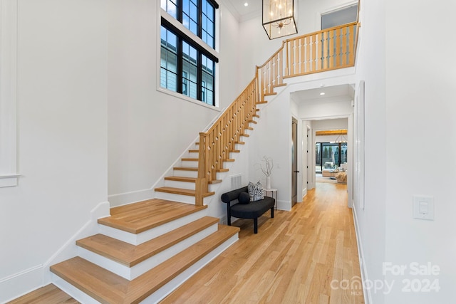 staircase with hardwood / wood-style flooring, a notable chandelier, and a high ceiling