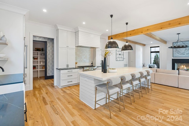 kitchen featuring premium range hood, a breakfast bar, white cabinets, and light hardwood / wood-style flooring