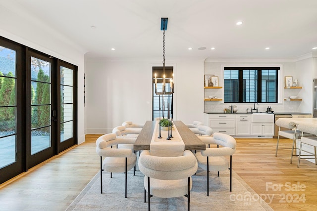 dining area with a notable chandelier, crown molding, light hardwood / wood-style flooring, and french doors