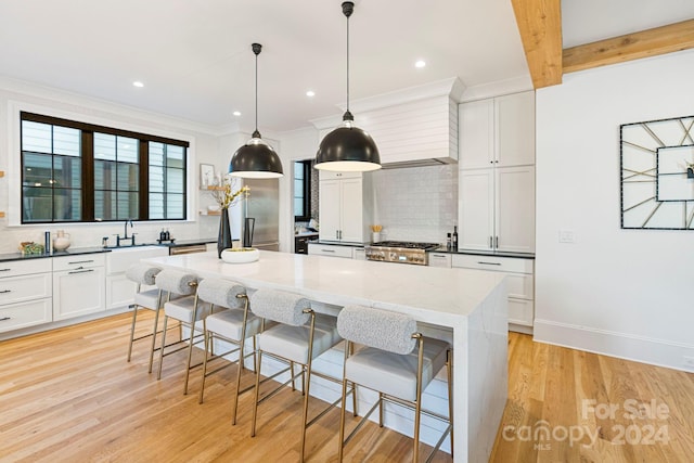 kitchen with hanging light fixtures, decorative backsplash, light stone countertops, light wood-type flooring, and white cabinetry