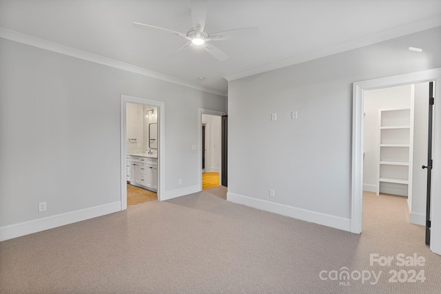 unfurnished bedroom with connected bathroom, a spacious closet, ceiling fan, and crown molding