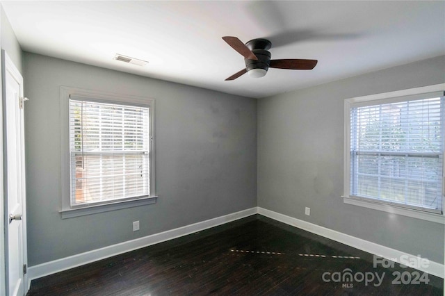 unfurnished room featuring ceiling fan, dark wood-type flooring, and a healthy amount of sunlight