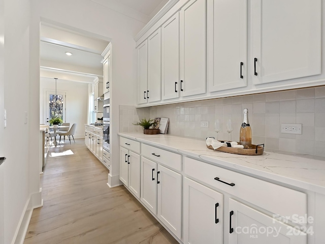 bar with white cabinets, light stone counters, backsplash, and light hardwood / wood-style flooring