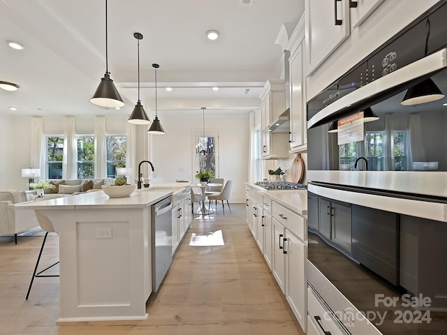 kitchen featuring white cabinets, pendant lighting, an island with sink, and stainless steel appliances