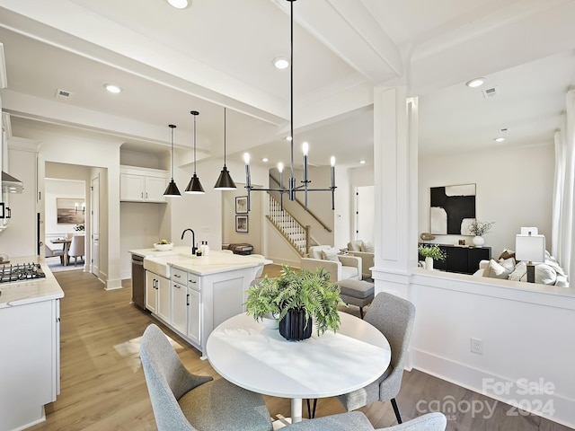 dining room featuring beam ceiling, sink, a notable chandelier, and light wood-type flooring