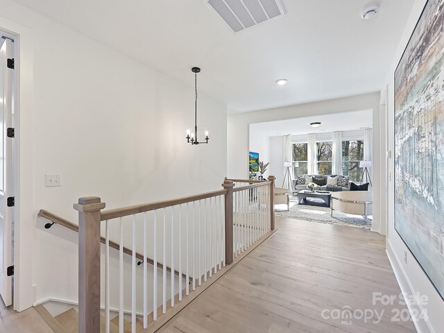 hall featuring light wood-type flooring and an inviting chandelier