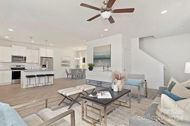 living room with light hardwood / wood-style flooring and ceiling fan