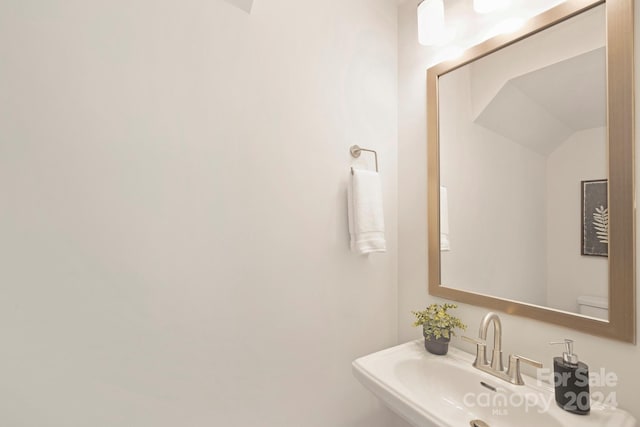 bathroom with toilet, lofted ceiling, and sink