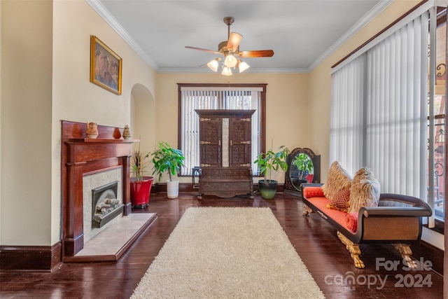 living area featuring dark hardwood / wood-style floors, ceiling fan, and crown molding