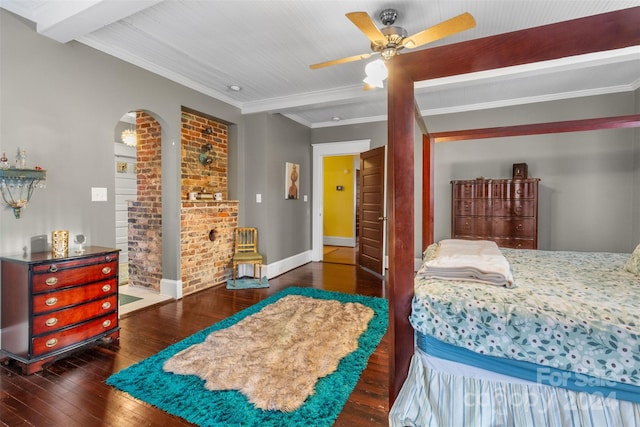 bedroom featuring ceiling fan, dark wood-type flooring, beamed ceiling, brick wall, and crown molding