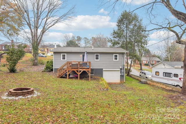 rear view of property with a yard, a garage, a deck, and an outdoor fire pit