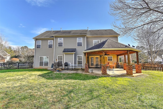 back of property with a lawn, ceiling fan, a patio area, and french doors