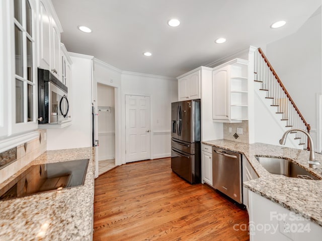 kitchen with hardwood / wood-style floors, sink, light stone counters, white cabinetry, and stainless steel appliances