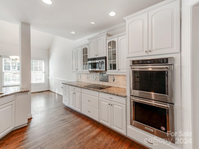 kitchen featuring appliances with stainless steel finishes, tasteful backsplash, light stone counters, wood-type flooring, and white cabinetry