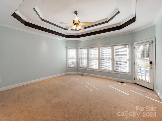 carpeted empty room featuring a raised ceiling, ceiling fan, and crown molding