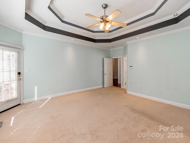 carpeted empty room featuring a tray ceiling, ceiling fan, and crown molding