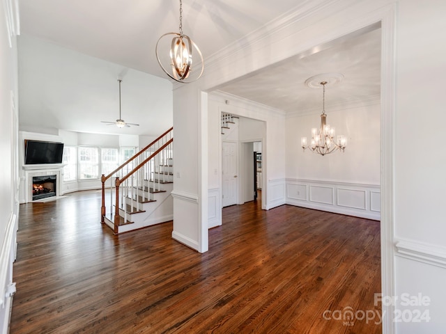 unfurnished living room featuring ceiling fan with notable chandelier, dark hardwood / wood-style flooring, and ornamental molding