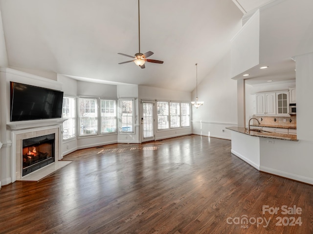 unfurnished living room featuring a fireplace, dark hardwood / wood-style floors, high vaulted ceiling, and a wealth of natural light