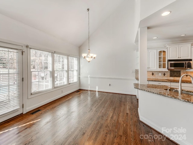 kitchen featuring plenty of natural light, light stone countertops, white cabinetry, and sink